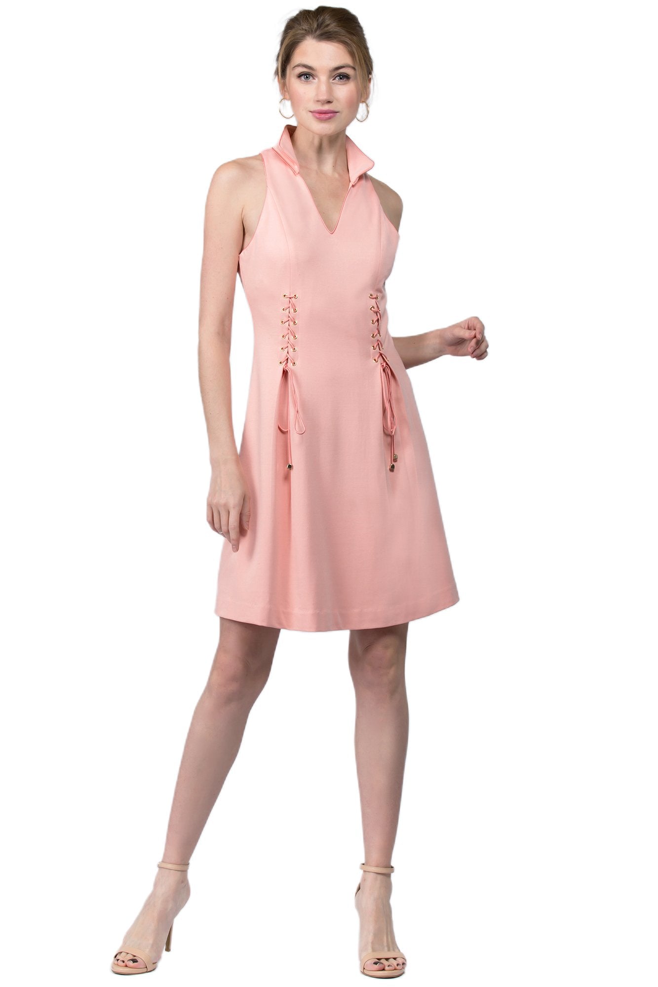 Model wearing sleeveless racer neck peachy pink short fit and flare wing tip collar dress with corset lace up ties at front waist.