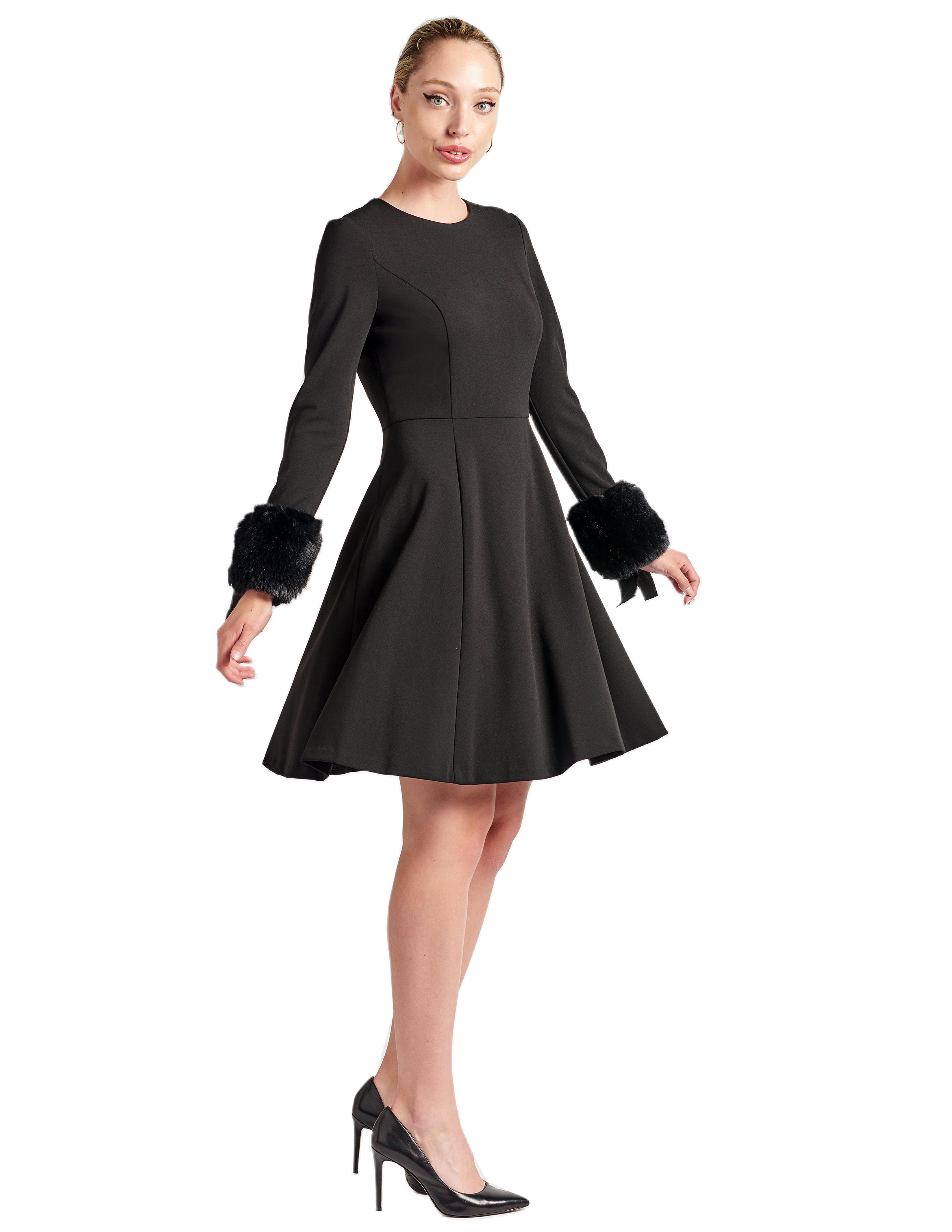 Model twirling in fit & flare black poly crepe long sleeve dress with sweetheart neckline & faux fur cuffs