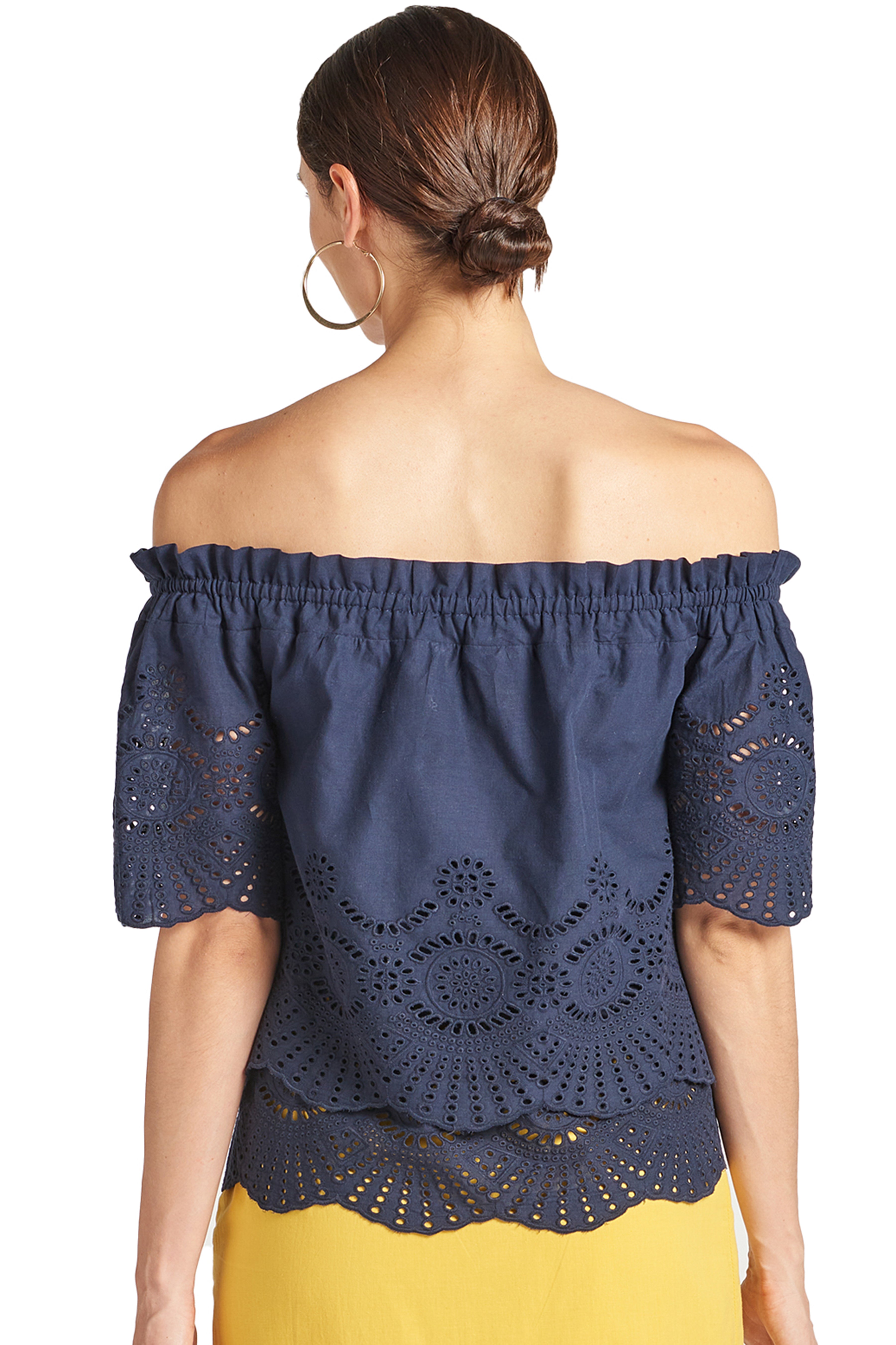 Back  view of model wearing navy off the shoulder cotton eyelet top with scalloped short sleeves and scalloped bottom hem.