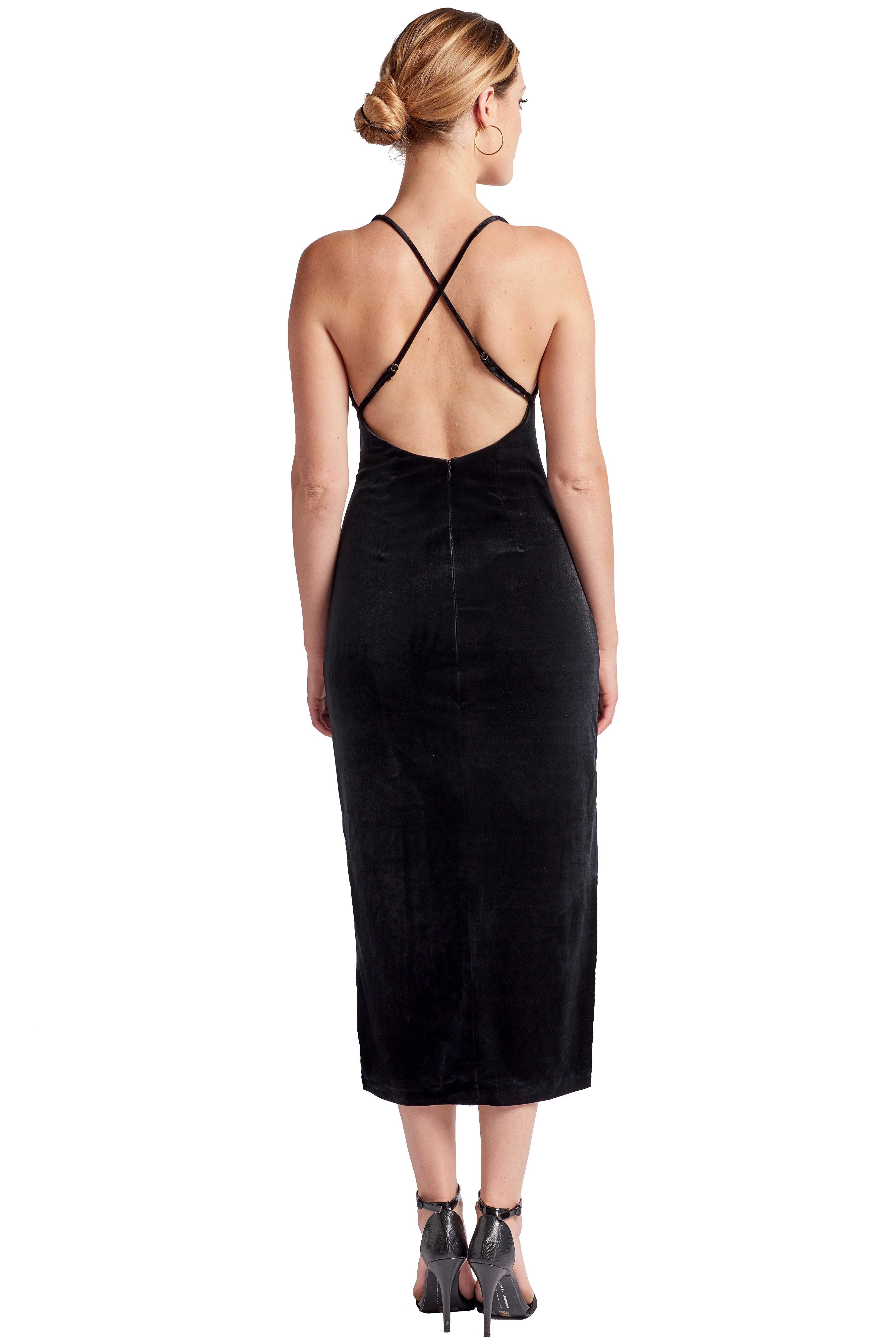 Back view of model wearing black stretch velvet midi dress with low back and criss cross spaghetti straps.