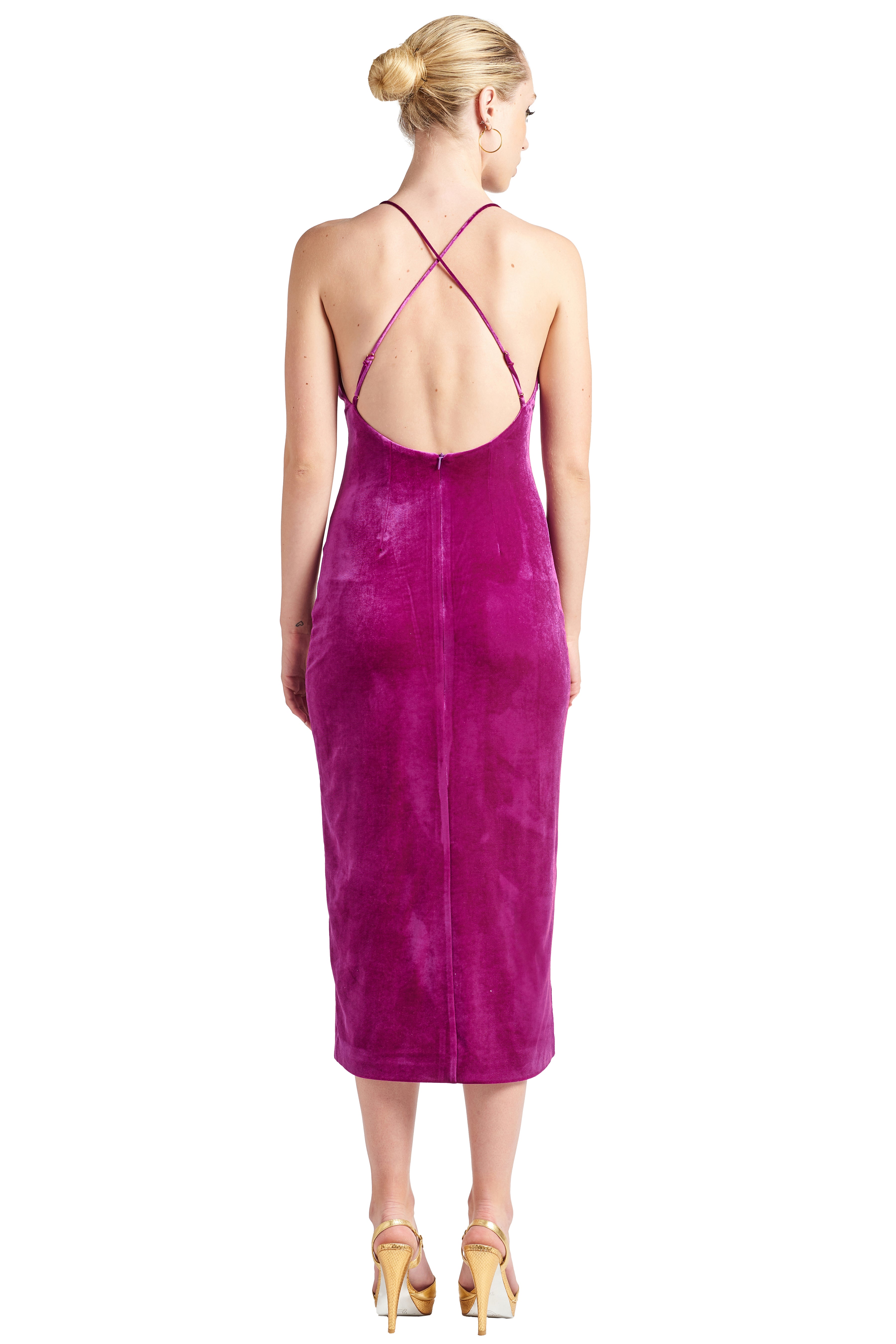 Back view of model wearing magenta stretch velvet midi dress with low back & criss cross adjustable spaghetti straps.