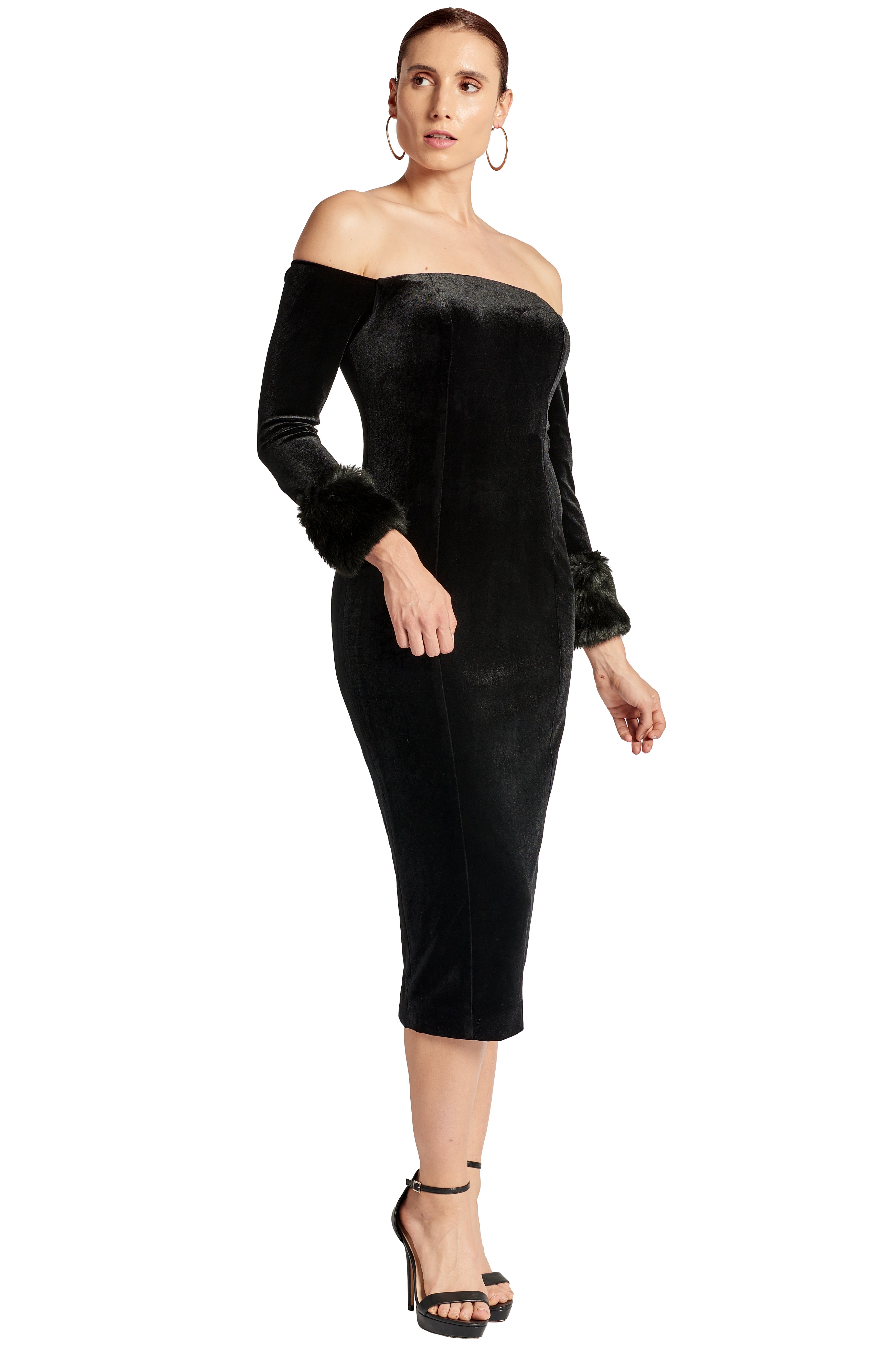 3/4 front view of model wearing the Simona Maghen Joia Dress, off the shoulder black velvet fitted midi dress with long sleeves and faux fur cuffs.