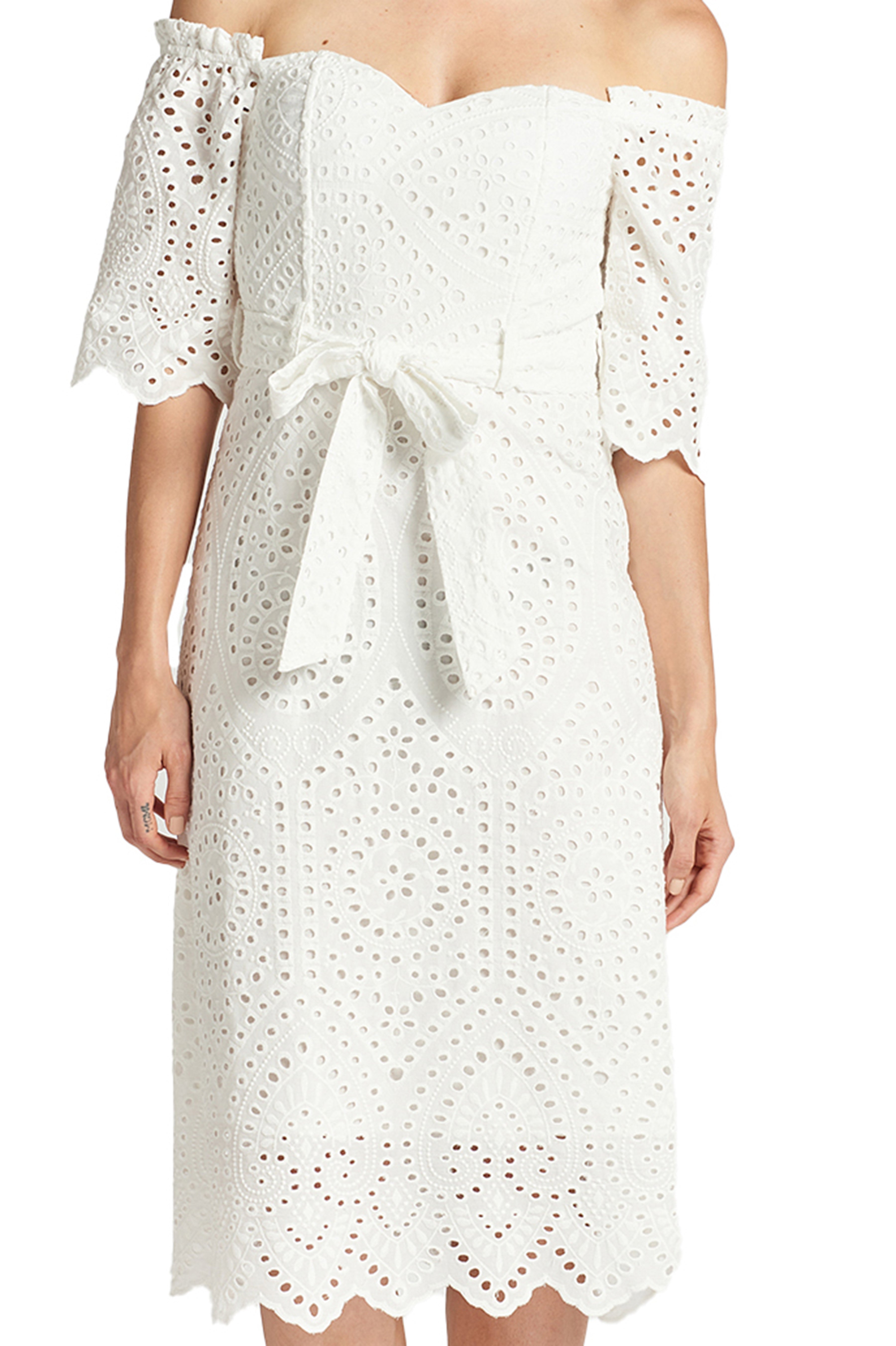 Close-up front view of model wearing the Simona Maghen Jasmine Dress, white cotton scalloped eyelet midi a-line dress with off the shoulder sweetheart neckline, self belt, and short sleeves.