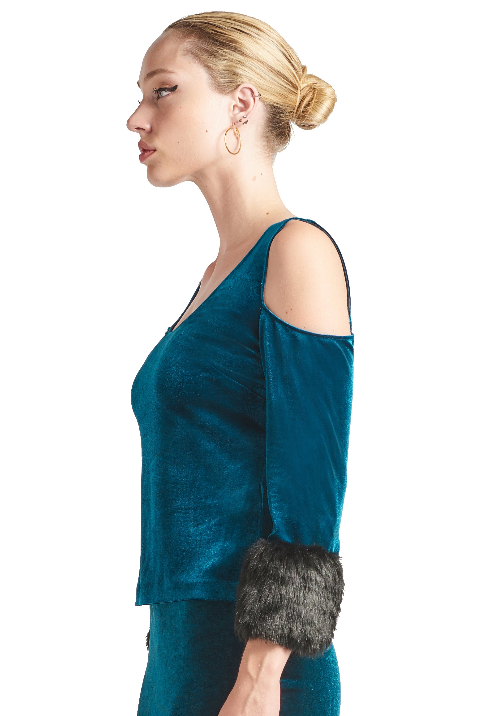 Side view of model wearing the Simona Maghen Mia Top, teal stretch velvet cut-out cold shoulder top with u-neckline, 3/4 sleeves and black faux fur cuffs.