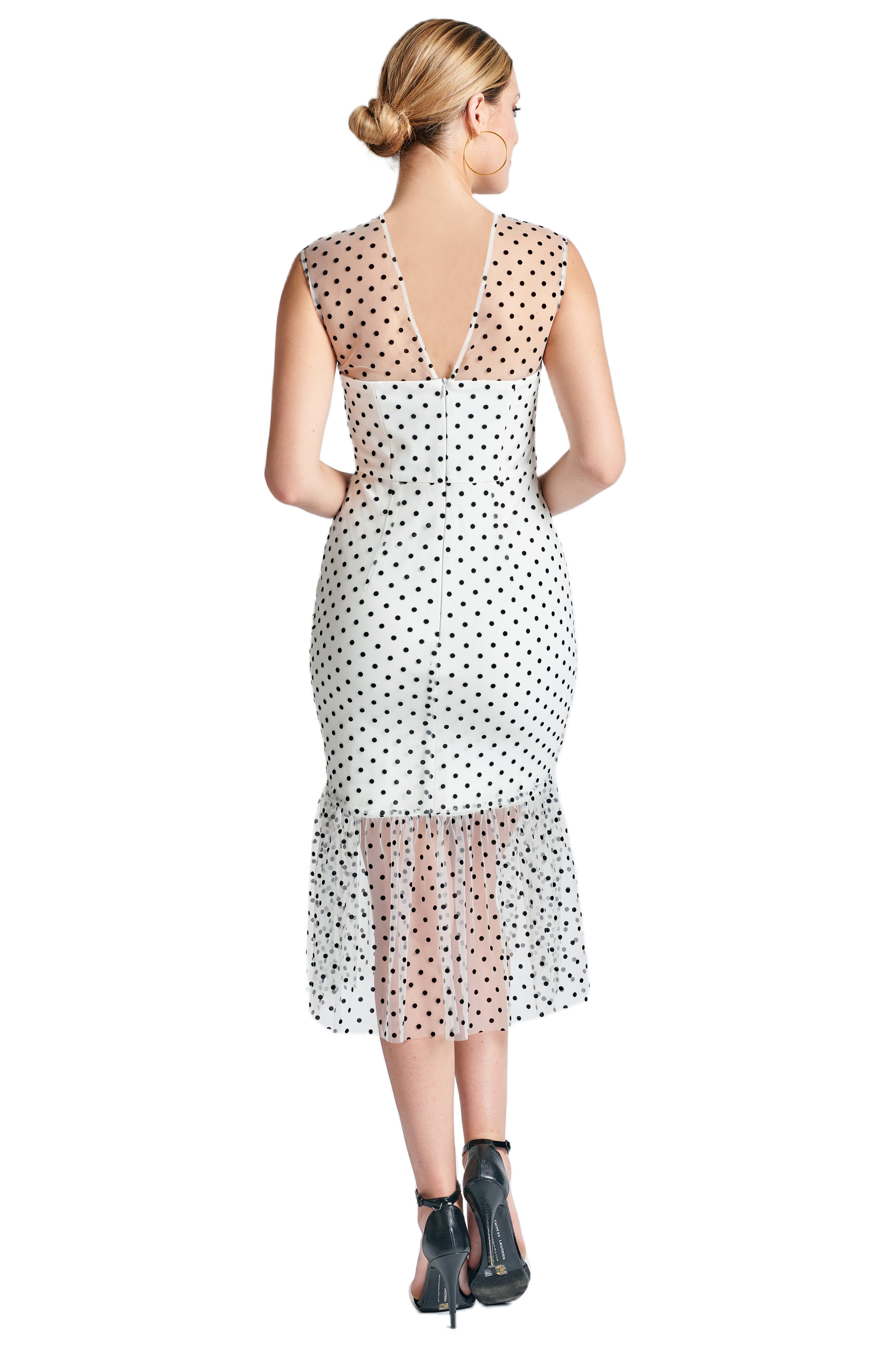 Back view of model wearing the Simona Maghen Muse Dress, white mesh with black polka dots sleeveless midi dress with sheer ruffle hem, and v-neckline.