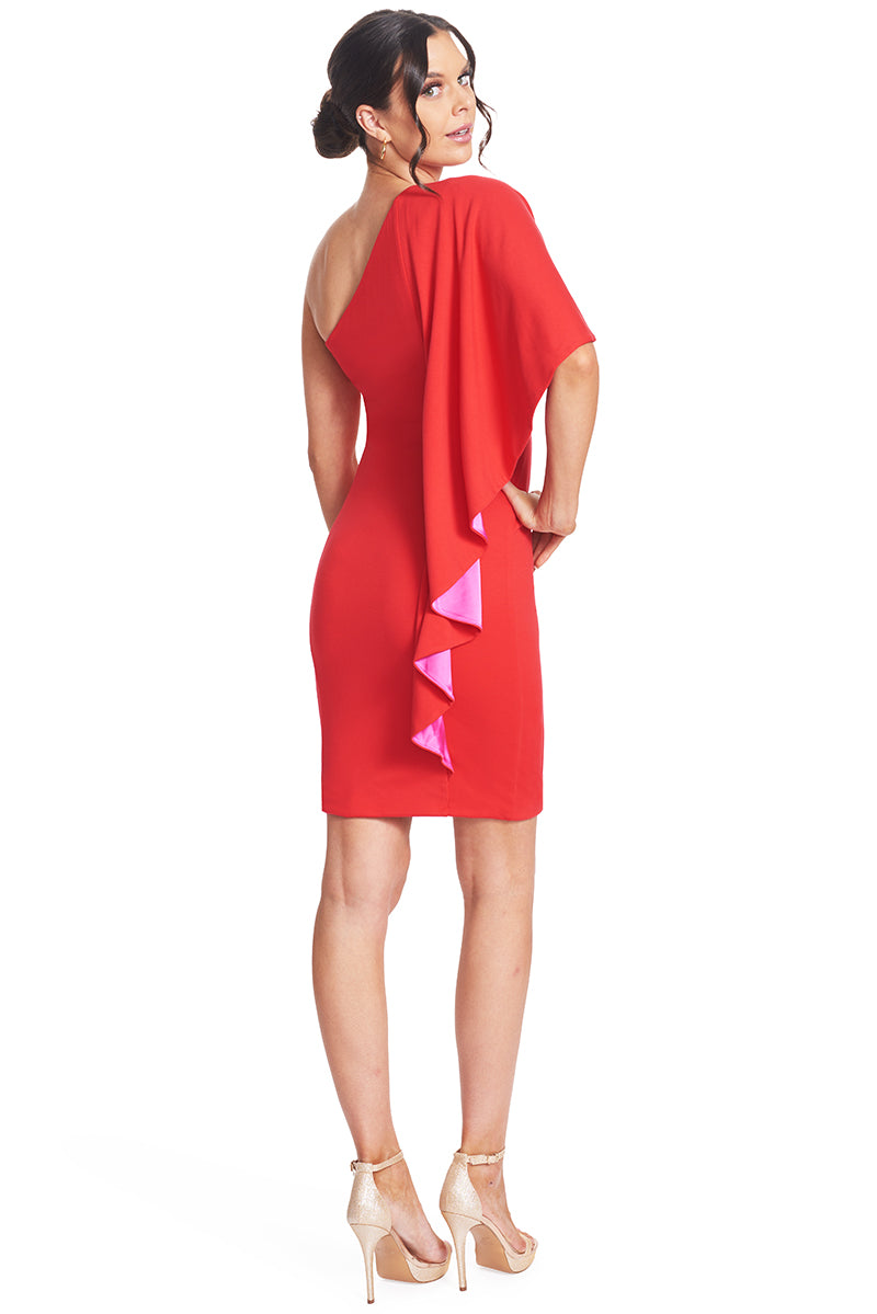 3/4 back view of model wearing  the Simona Maghen Shero Dress, red above the knee body-con Ponte asymmetric cape dress with fuchsia contrast satin inside cape.
