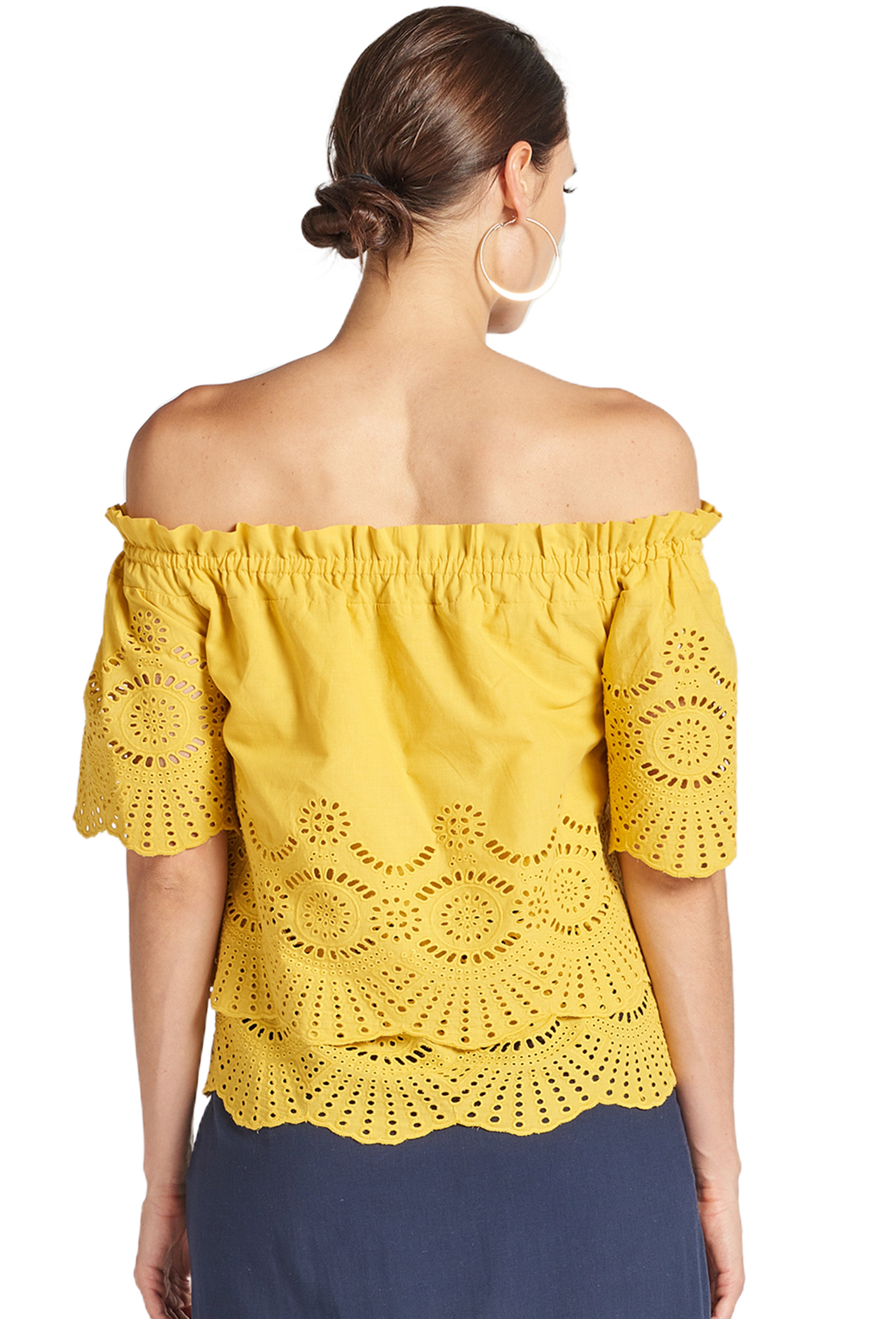 Back view of model wearing yellow off the shoulder cotton eyelet top with scalloped short sleeves and scalloped bottom hem.
