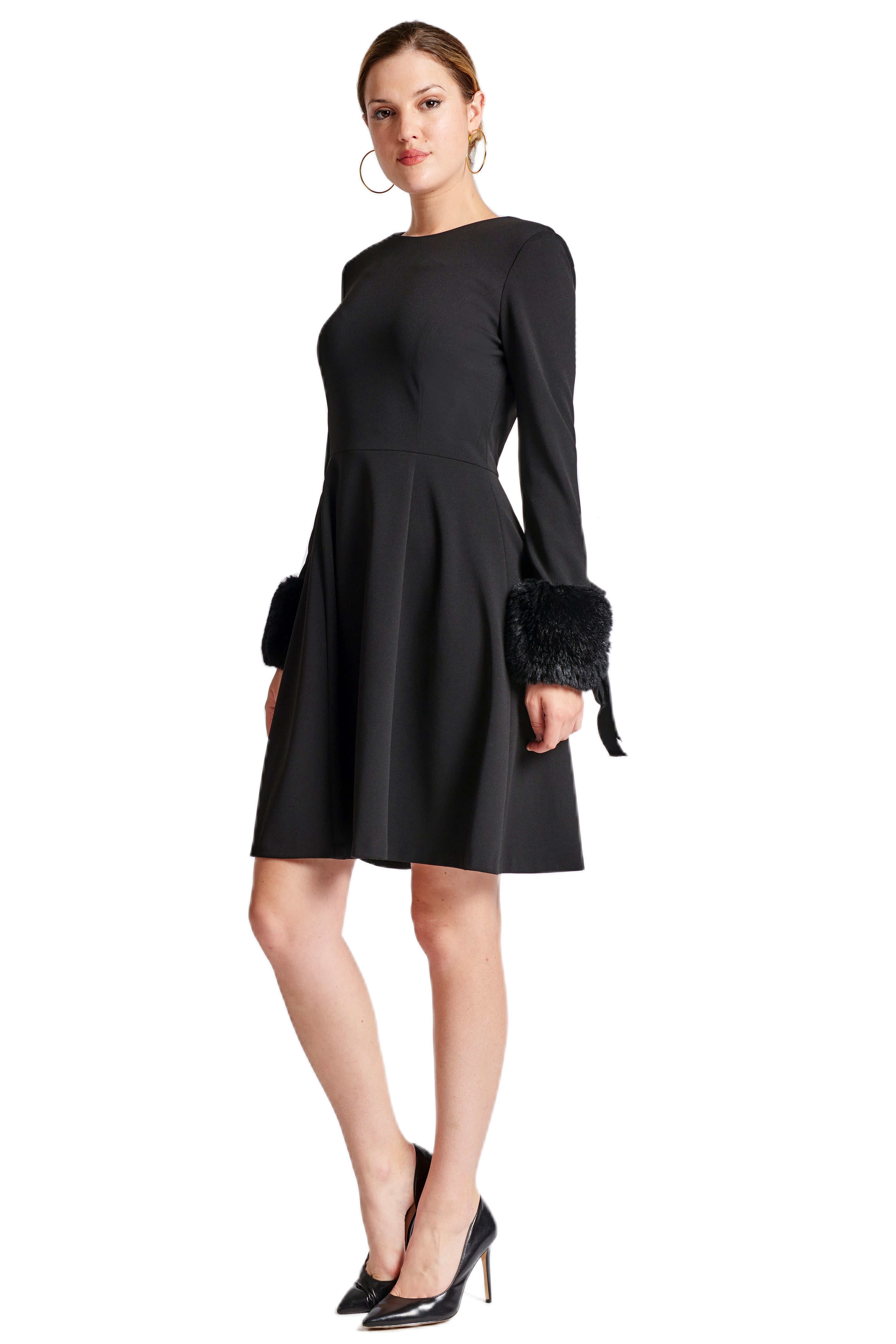 Model wearing fit & flare black poly crepe long sleeve dress with sweetheart neckline & faux fur cuffs.