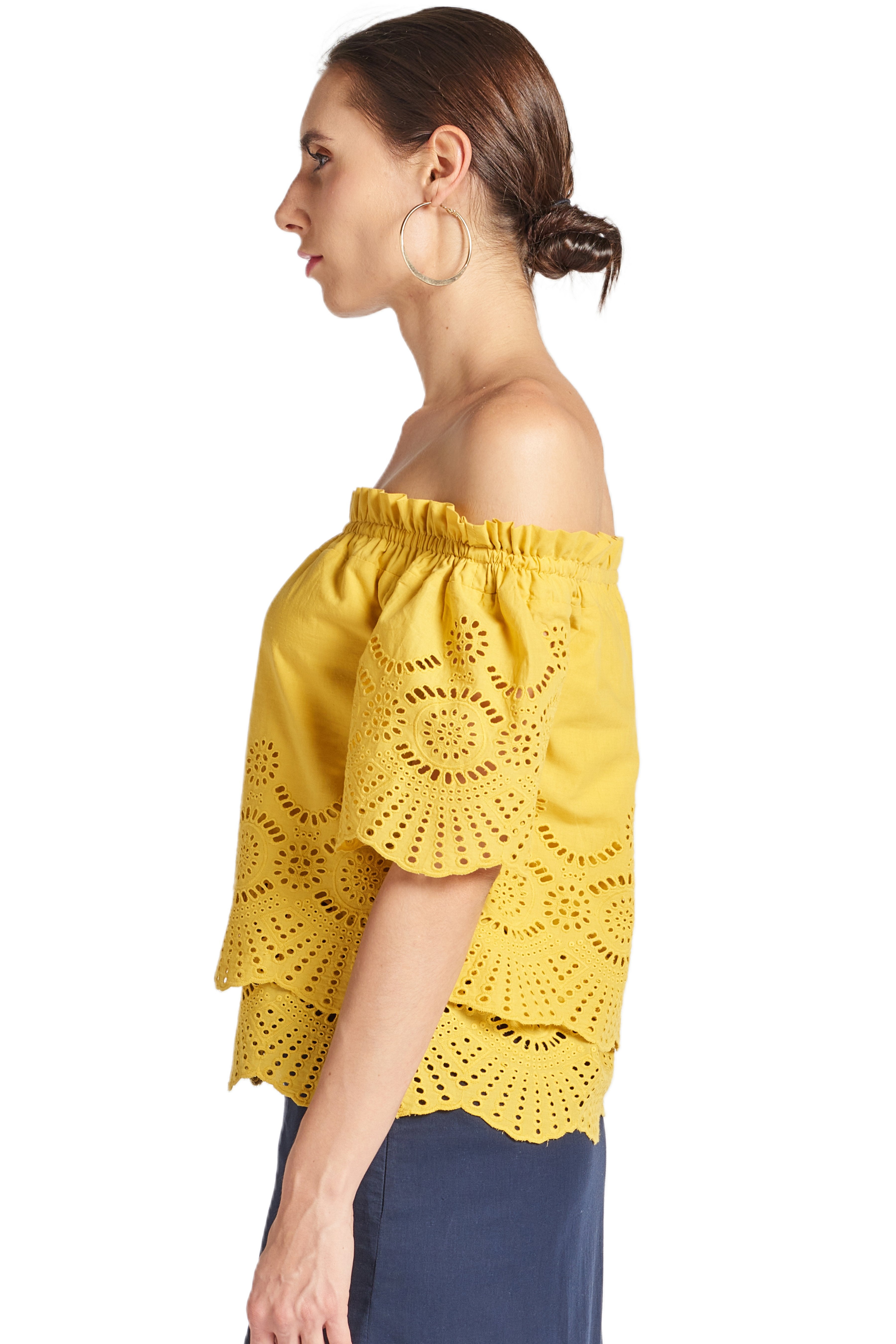 Side view of model wearing yellow off the shoulder cotton eyelet top with scalloped short sleeves and scalloped bottom hems.
